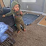 child, toddler, baby, hooded, standing, barefoot, indoor, living_room, couch, carpet, blanket, window, blinds, pacifier, clothing, green_outfit, portrait, home, daylight, smiling
