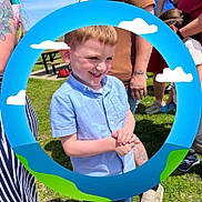 Jakobi joined the competition — help win amazing prizes! child, boy, smiling, blue_shirt, outdoor, sunny, grass, people, tattoos, hand_clasped, circular_frame, clouds, green_hills, casual_clothing, happy, portrait, daylight, playful_frame, event, park