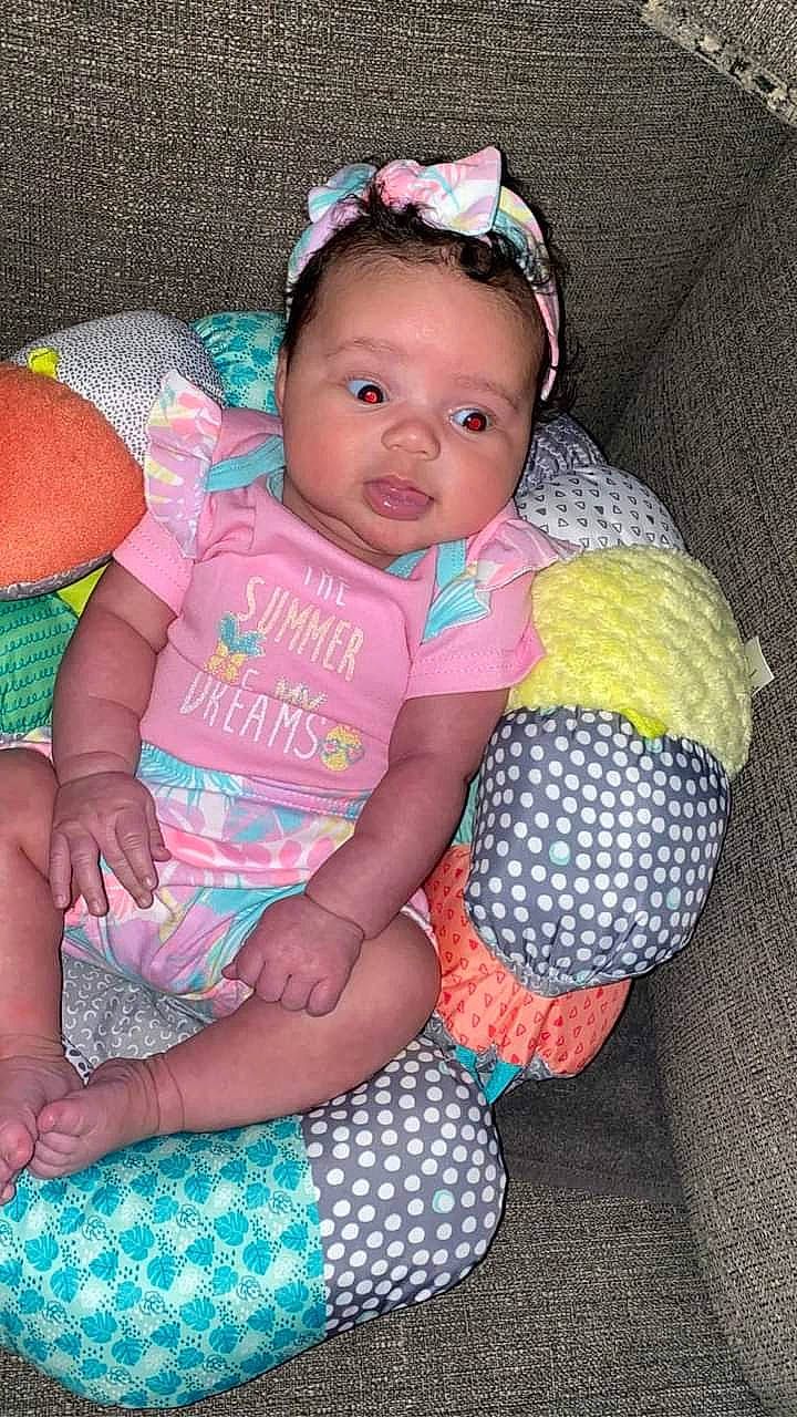 Samaya is registered to the contest to win money with this photo: baby, baby_products, baby_toddler_clothing, cheek, child, comfort, eye, happy, head, headgear, magenta, organ, pattern, person, pink, purple, sitting, skin, textile, thigh