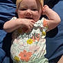 Sophia is registered to the contest to win money with this photo: baby, child, infant, headband, yellow_bow, smile, happy, floral_pattern, clothing, onesie, shorts, green_shorts, lying_down, blanket, blue_blanket, cute, portrait, hand, face, playful
