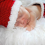 Rowan joined the competition — help win amazing prizes! baby, newborn, sleeping, red_hat, knitted_hat, white_fur, cozy, holiday, christmas, cute, infant, soft_texture, portrait, peaceful, resting, skin, wrapped, closeup, child, festive