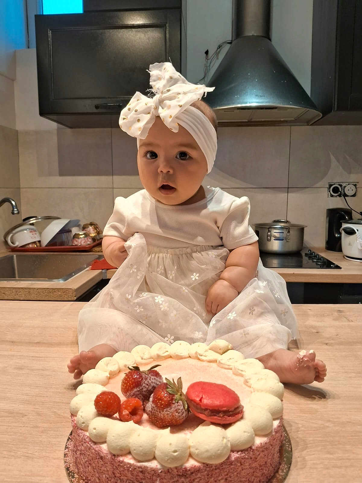 Christelle participe au concours pour gagner de l'argent avec cette photo : appliance, baby, cake, child, cooking, countertop, cute, dessert, food, foot, frosting, headband, indoor, kitchen, macaron, portrait, pots, sink, strawberries, white_dress