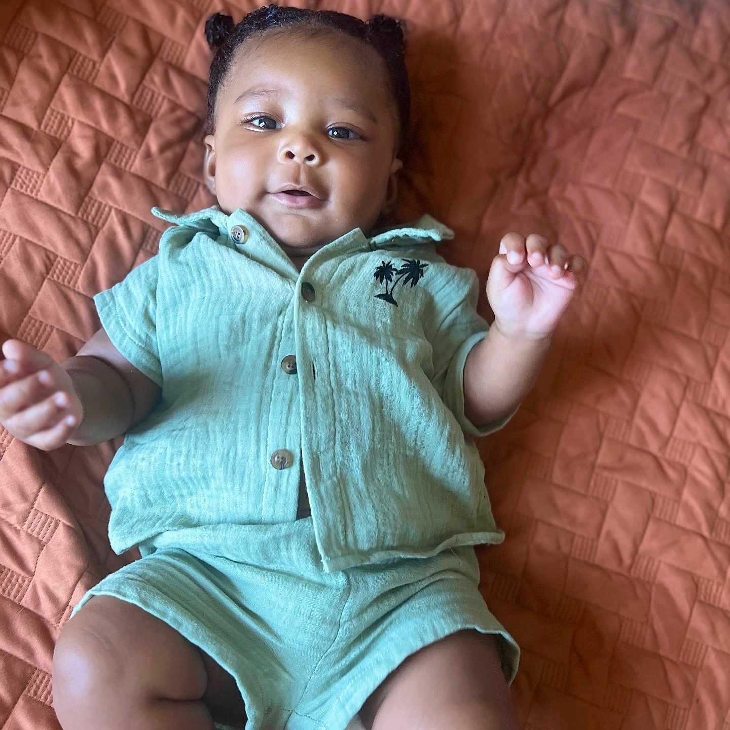Queron joined the competition — help win amazing prizes! baby, bedspread, blanket, child, clothing, cute, expression, face, green_outfit, hands, indoor, infant, lying_down, palm_tree, portrait, resting, shirt, shorts, skin, texture