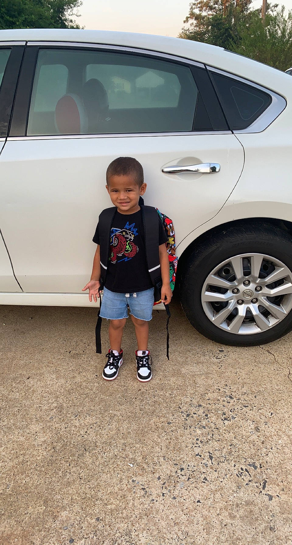 Kameron is registered to the contest to win money with this photo: alloy_wheel, automotive_design, automotive_exterior, automotive_lighting, automotive_tire, black, bumper, car, hood, hubcap, joy, land_vehicle, light, motor_vehicle, person, photograph, shorts, standing, tire, vehicle