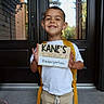 child, kindergarten, school, first_day, backpack, smiling, happy, portrait, standing, outdoor, front_door, home, school_sign, peace_sign, boy, white_shirt, beige_pants, yellow_backpack, daylight, family_photo