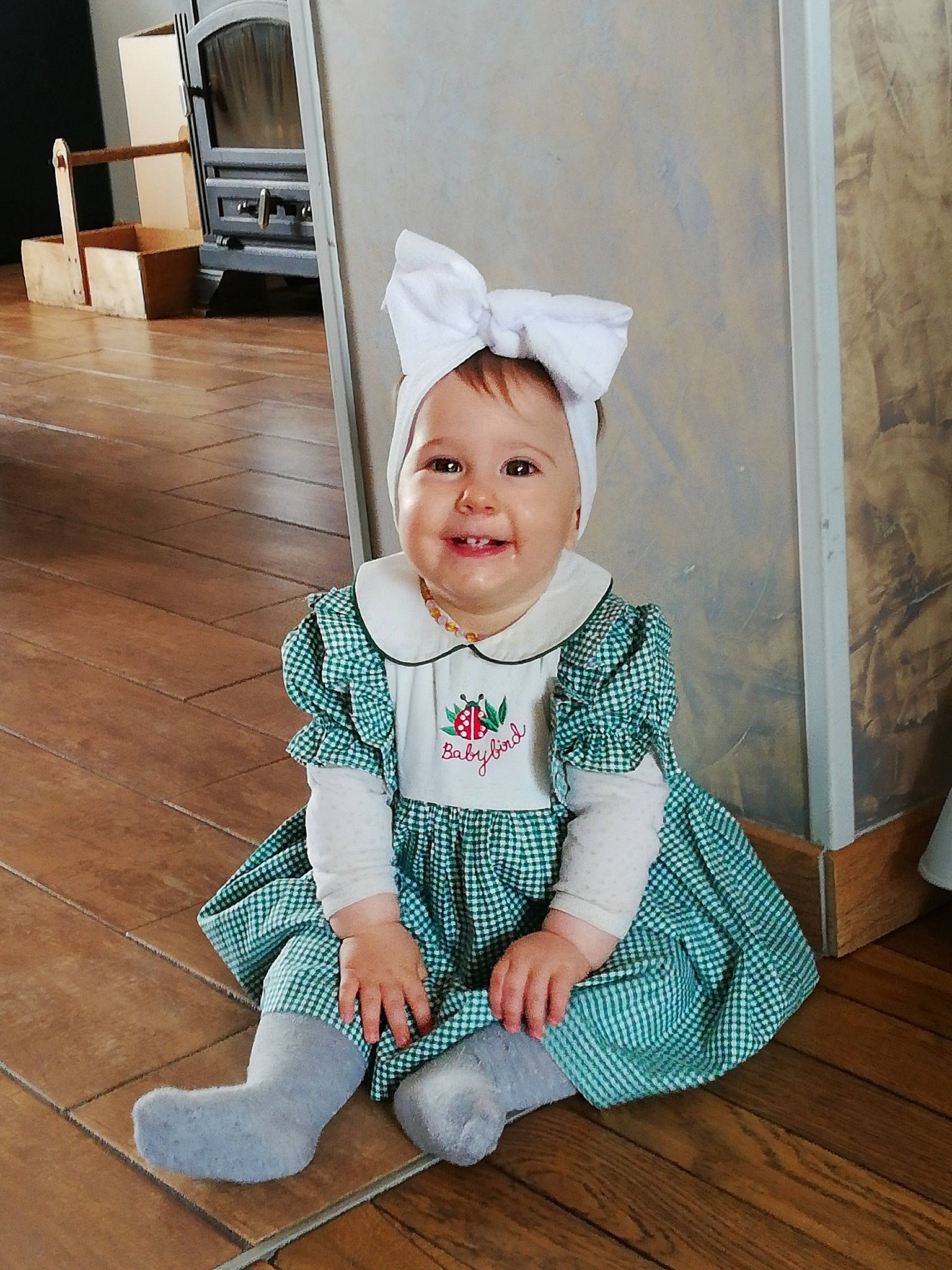 Lola a rejoint le concours — aidez-le/la à gagner de superbes lots ! baby_toddler_clothing, child, costume, floor, flooring, headgear, joy, person, sitting, sleeve, smile, toddler, wood
