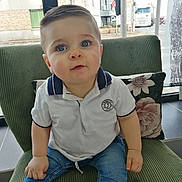 Livio a rejoint le concours — aidez-le/la à gagner de superbes lots ! toddler, child, blue_eyes, white_polo, denim_jeans, green_chair, floral_pillow, indoor, window, street_view, short_hair, cute, portrait, sitting, casual_clothing, daylight, person, baby, expression, home