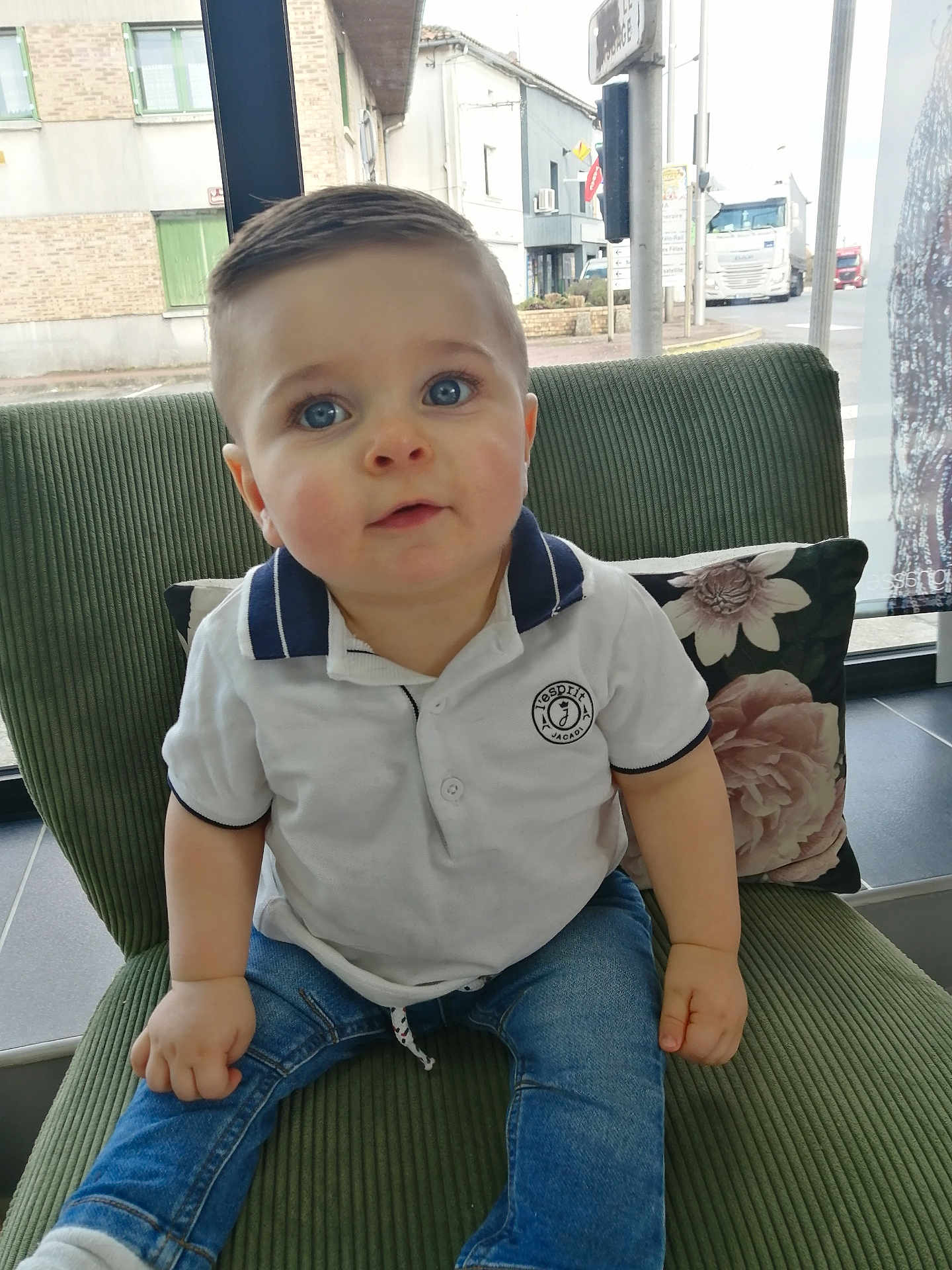 Livio a rejoint le concours — aidez-le/la à gagner de superbes lots ! toddler, child, blue_eyes, white_polo, denim_jeans, green_chair, floral_pillow, indoor, window, street_view, short_hair, cute, portrait, sitting, casual_clothing, daylight, person, baby, expression, home