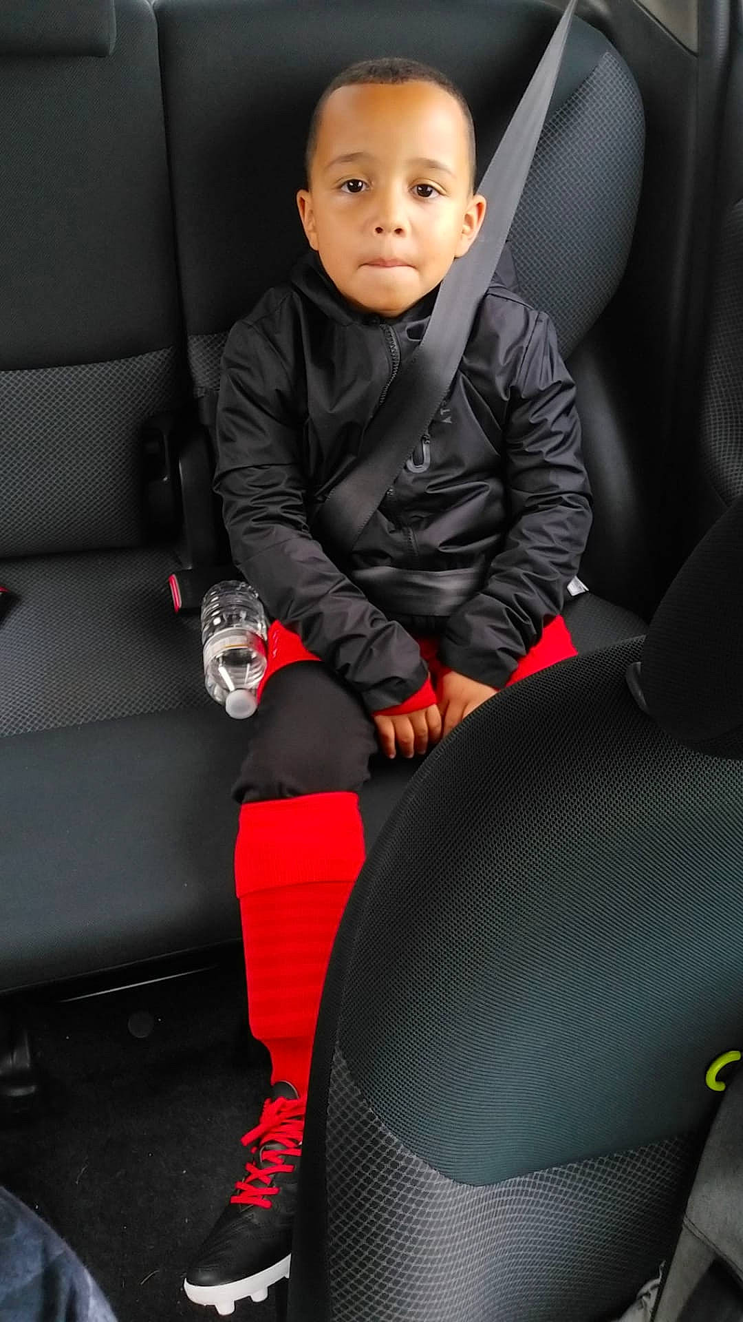 Ryan a rejoint le concours — aidez-le/la à gagner de superbes lots ! auto_part, car, car_seat, car_seat_cover, child, compact_car, family_car, luxury_vehicle, person, red, sitting, smile, tights, toddler, vehicle