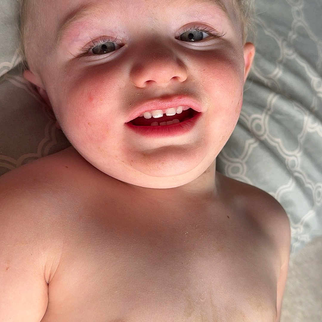 Jefferson is registered to the contest to win money with this photo: baby, bare_chest, blanket, child, closeup, expression, face, happy, head, indoors, infant, light, pattern, person, portrait, skin, smiling, teeth, toddler, young_child