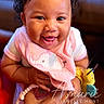 baby, smiling, pink_bib, elephant_embroidery, toy, hand, happy, closeup, infant, cute, child, person, portrait, indoors, warm_lighting, cheerful, holding, clothing, cute_expression, adorable