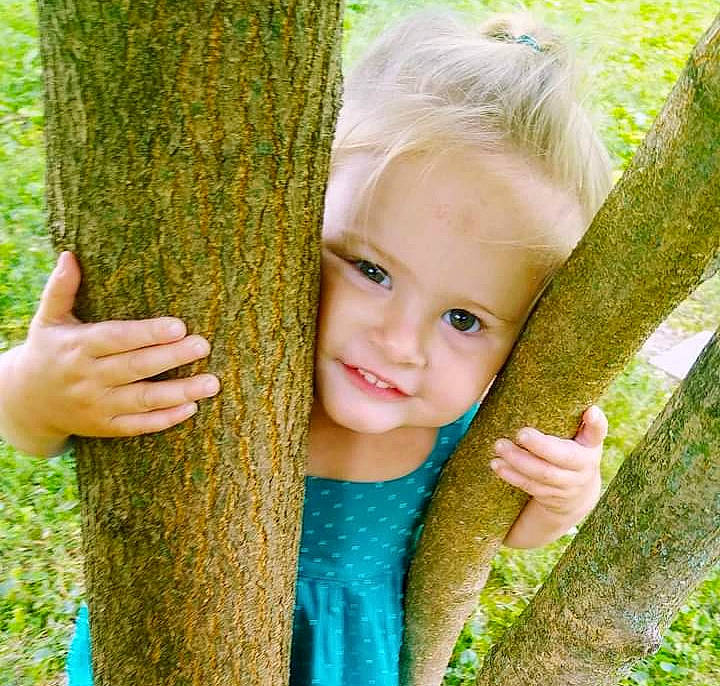 Kynleigh is registered to the contest to win money with this photo: biome, botany, branch, finger, gesture, grass, green, hand, happy, human_body, joy, leaf, nature, people_in_nature, person, plant, smile, terrestrial_plant, trunk, vegetation