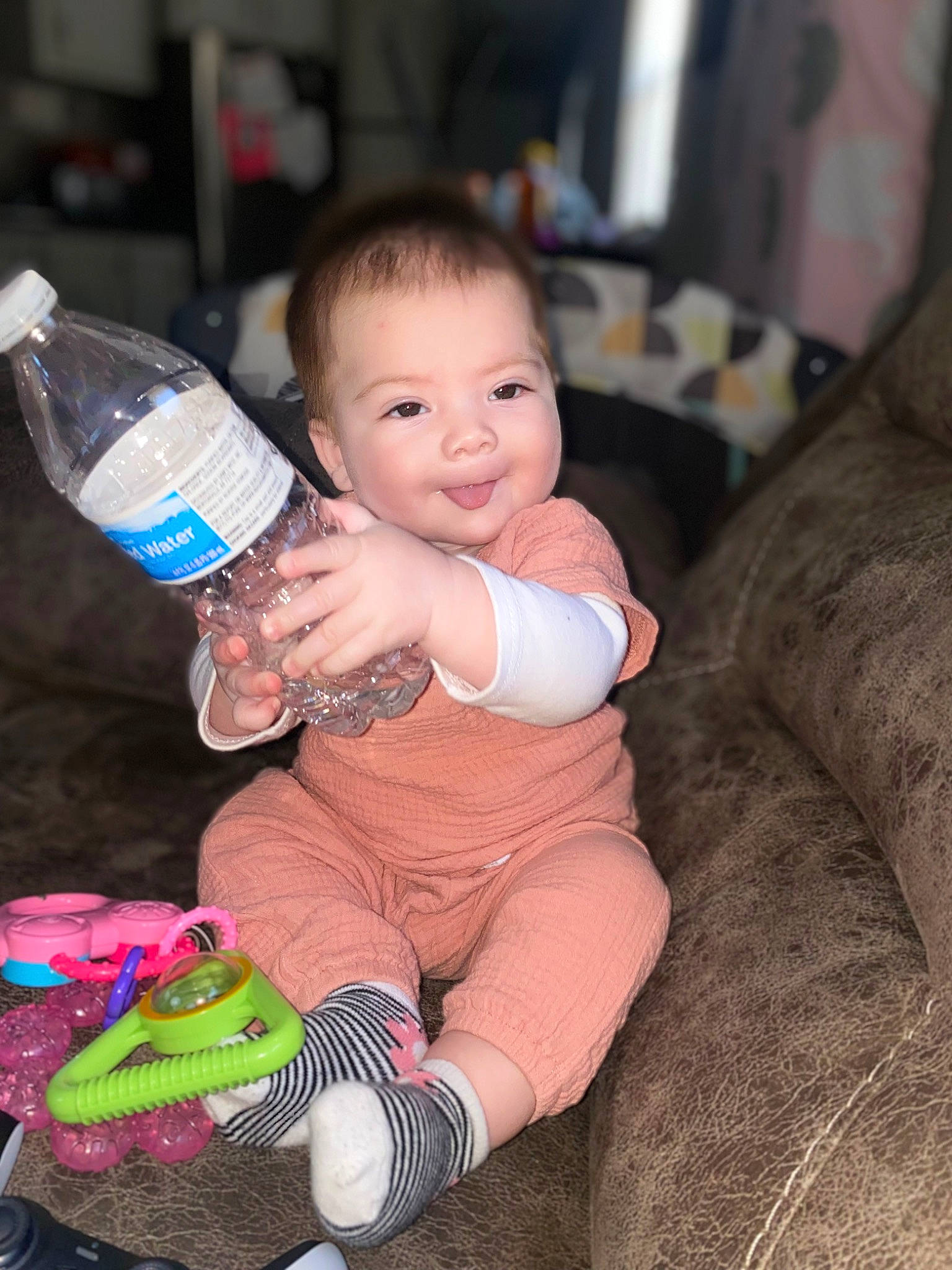 Ariella is registered to the contest to win money with this photo: baby, baby_toddler_clothing, bottle, bottle_cap, bottled_water, cheek, child, comfort, drinking_water, drinkware, facial_expression, finger, happy, joy, people, person, plastic_bottle, sitting, skin, smile