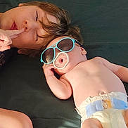 Dusty Ray is registered to the contest to win money with this photo: baby, child, cute, diaper, face, finger, hair, hand, indoor, lying_down, pacifier, person, playful, relaxed, resting, skin, sleeping, sunglasses, toddler, two_children