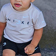 Kingstyn is registered to the contest to win money with this photo: child, toddler, sitting, clothing, nike, shorts, shirt, sneakers, sportswear, curly_hair, blue_eyes, outdoor, concrete, casual, portrait, cute, expression, person, footwear, fashion