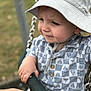 toddler, child, swing, hat, sunhat, shirt, patterned_clothing, hand, playground, outdoor, chains, focus, portrait, baby, expression, holding, support, daylight, grass, seat