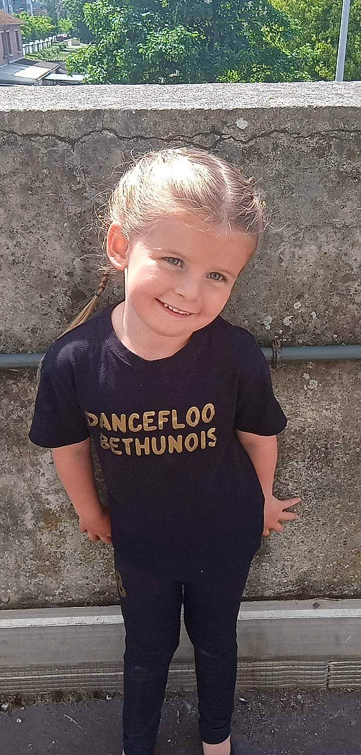 Naelle a rejoint le concours — aidez-le/la à gagner de superbes lots ! active_shirt, asphalt, child, concrete, electric_blue, flash_photography, grey, happy, iris, joy, lip, long_sleeved_t_shirt, person, portrait_photography, sitting, sleeve, smile, sportswear, standing, t_shirt