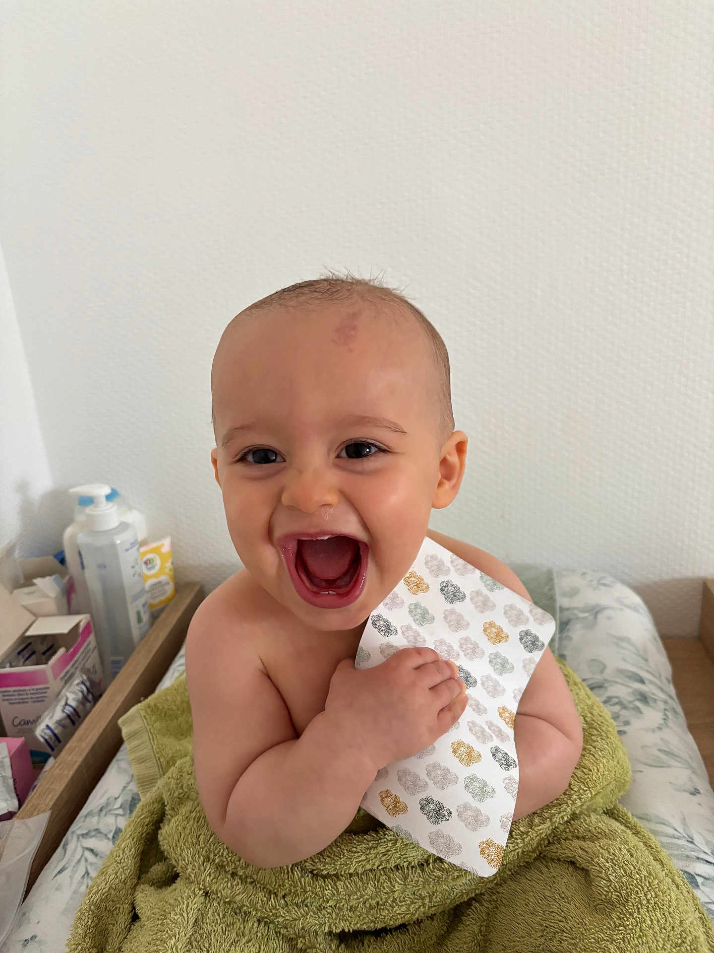 Livio participe au concours pour gagner de l'argent avec cette photo : baby, child, smiling, laughing, towel, indoor, face, hand, skin, person, happy, pattern, paper, infant, cushion, baby_care, healthcare, sitting, young_child, background