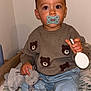 Livio a rejoint le concours — aidez-le/la à gagner de superbes lots ! toddler, child, pacifier, plush_toy, sweater, teddy_bear_pattern, jeans, sock, indoor, cushion, floor, wood, wall, toy, person, baby, cute, sitting, clothing, hand