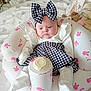 baby, doll, inflatable_chair, bunny_pattern, bow, dress, white_clothing, bottle, indoor, bed, blanket, stuffed_animal, toy, infant, pink, face, headwear, sitting, soft_toys, cute