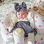 Nevaeh is registered to the contest to win money with this photo: baby, infant, child, bow, headband, houndstooth, white_clothing, inflatable_seat, pink_bunnies, plush_toy, bed, blanket, socks, cute, indoors, portrait, soft_lighting, calm, seated, person