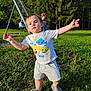 toddler, child, park, grass, trees, swing, playground, sunlight, person, shorts, tshirt, footwear, outdoor, summer, nature, family, casual_clothing, greenery, play, fun