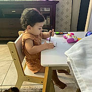 Harper joined the competition — help win amazing prizes! toddler, child, drawing, table, chair, toy, phone_toy, dog, curly_hair, wooden_furniture, living_room, television, cabinet, photo_frame, floor_tile, carpet, clothing, foot, indoor, person