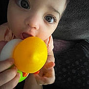 Harper joined the competition — help win amazing prizes! baby, background, chewing, child, close_up, colorful, curious, cute, expression, face, hand, holding, indoor, infant, person, playful, skin, toy, yellow, young