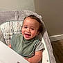 toddler, child, smiling, baby_seat, bib, curly_hair, indoor, cushion, gray_shirt, happy, face, person, wooden_floor, wall, home, infant, cute, young_child, comfort, portrait