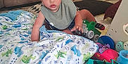 Noah is registered to the contest to win money with this photo: toddler, child, toy, blanket, play_mat, truck, green_toy, couch, indoor, carpet, sitting, curious, clothing, bib, floor, home, person, baby, cute, playtime