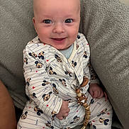 Sohan a rejoint le concours — aidez-le/la à gagner de superbes lots ! baby, child, smiling, mickey_mouse, onesie, pacifier_clip, wooden_toy, blanket, soft_texture, happy, cute, infant, clothing, seated, indoors, closeup, portrait, face, hand, comfort