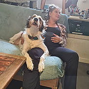 Wido participe au concours pour gagner de l'argent avec cette photo : woman, dog, couch, indoor, relaxed, casual, plant, table, art_supplies, slippers, black_clothing, furniture, pet, lap, light, window, wood, expression, home, cozy