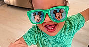 Milo joined the competition — help win amazing prizes! bright_colors, casual, child, close_up, curly_hair, dinosaur_pattern, footwear, green_clothing, happy, holding_hand, indoor, joyful, kitchen, person, playful, portrait, smiling, sunglasses, toddler, young_child