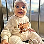 Milo is registered to the contest to win money with this photo: baby, child, infant, knitted_hat, bear_motif, socks, cozy_clothing, smiling, cute, sitting, outdoor, sunlight, warm_clothes, happy, portrait, closeup, candid, soft_texture, expression, young_child