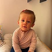 Inaya a rejoint le concours — aidez-le/la à gagner de superbes lots ! toddler, child, baby, sitting, pink_top, jeans, barefoot, bow, curly_hair, cushion, decor, shelf, shoes, indoor, minimalist, portrait, cute, curious, soft_lighting, face