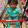 baby, candy, cart_handle, child, colorful, curly_hair, dinosaur_pattern, greeting_cards, gripping, grocery_store, indoor, portrait, retail_aisle, shopping, shopping_cart, sitting, snacks, store, toddler, turquoise_clothing
