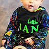 baby, infant, child, sitting, blue_eyes, colorful_clothing, splatter_pattern, carpet, wooden_sign, months_marker, cute, portrait, indoor, smiling, young_child, hands, feet, bright_eyes, clothing, face