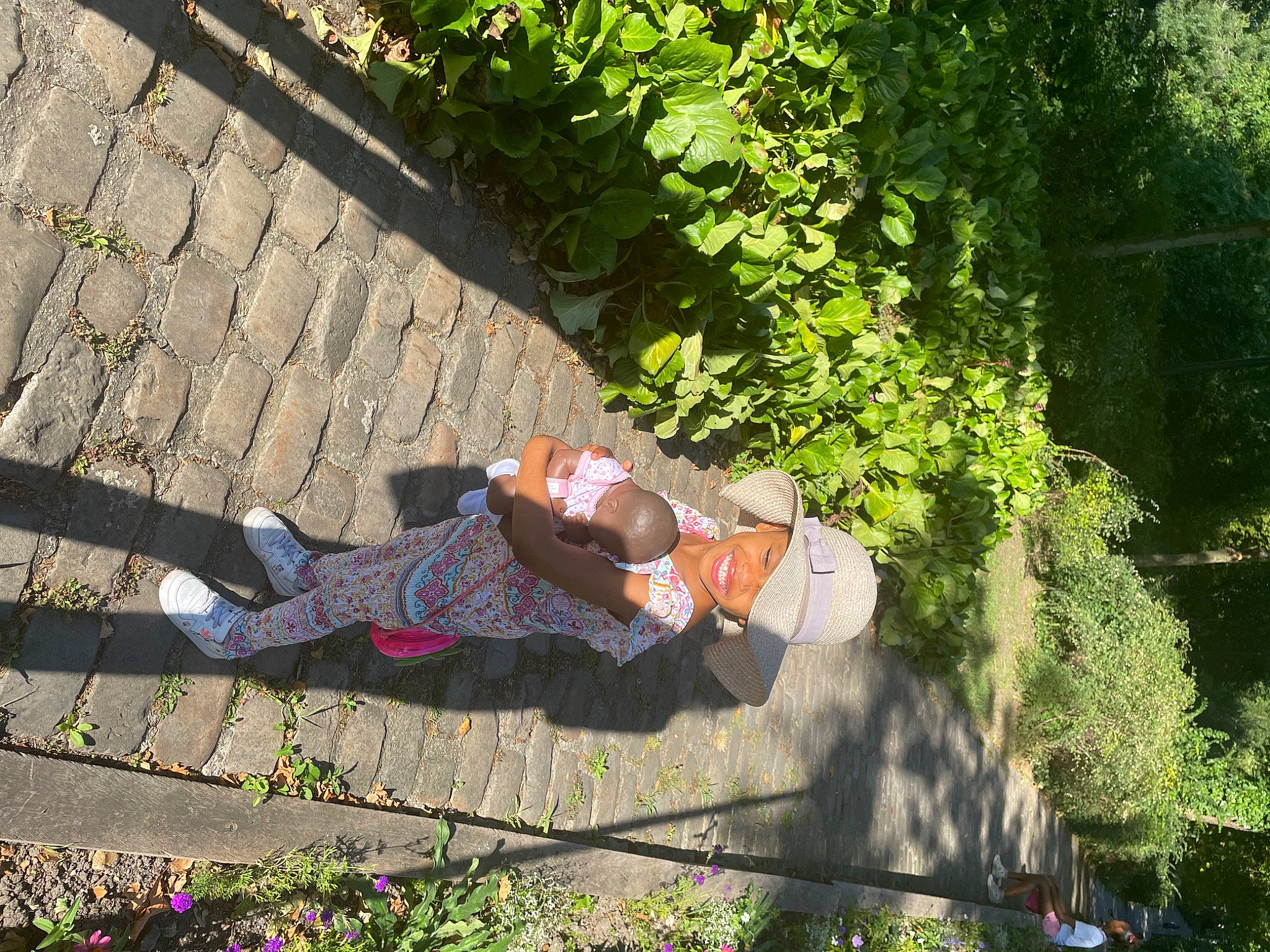 Mitzi participe au concours pour gagner de l'argent avec cette photo : asphalt, city, garden, grass, groundcover, headwear, human_leg, joy, landscape, leaf, leisure, people_in_nature, person, plant, recreation, road, road_surface, shadow, shrub, sidewalk