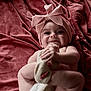 baby, infant, smile, headband, bow, blanket, soft_texture, skin, cute, happy, hand, foot, lying_down, close_up, indoors, child, portrait, playful, toddler, expression