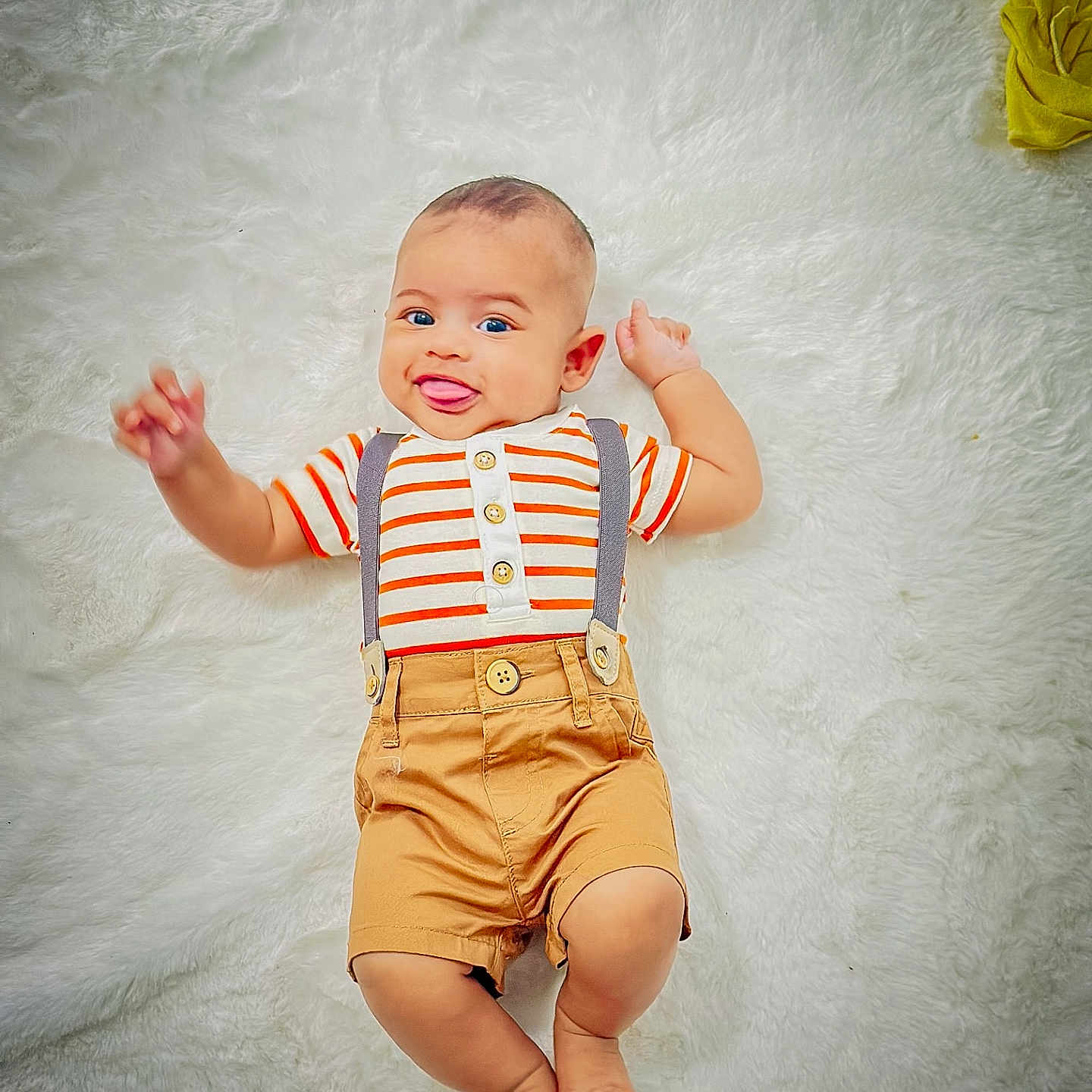 Thabit is registered to the contest to win money with this photo: baby, barefoot, casual_clothing, child, cute, funny_face, happy, indoor, infant, lying_down, person, playful, portrait, shorts, small_child, smiling, striped_shirt, suspenders, tongue_out, white_rug