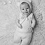 baby, infant, smiling, cute, knitted_clothing, bear_ears, plush_blanket, soft_texture, black_and_white, portrait, lying_down, happy, child, cozy, adorable, small_hands, baby_clothes, infant_fashion, warm, peaceful