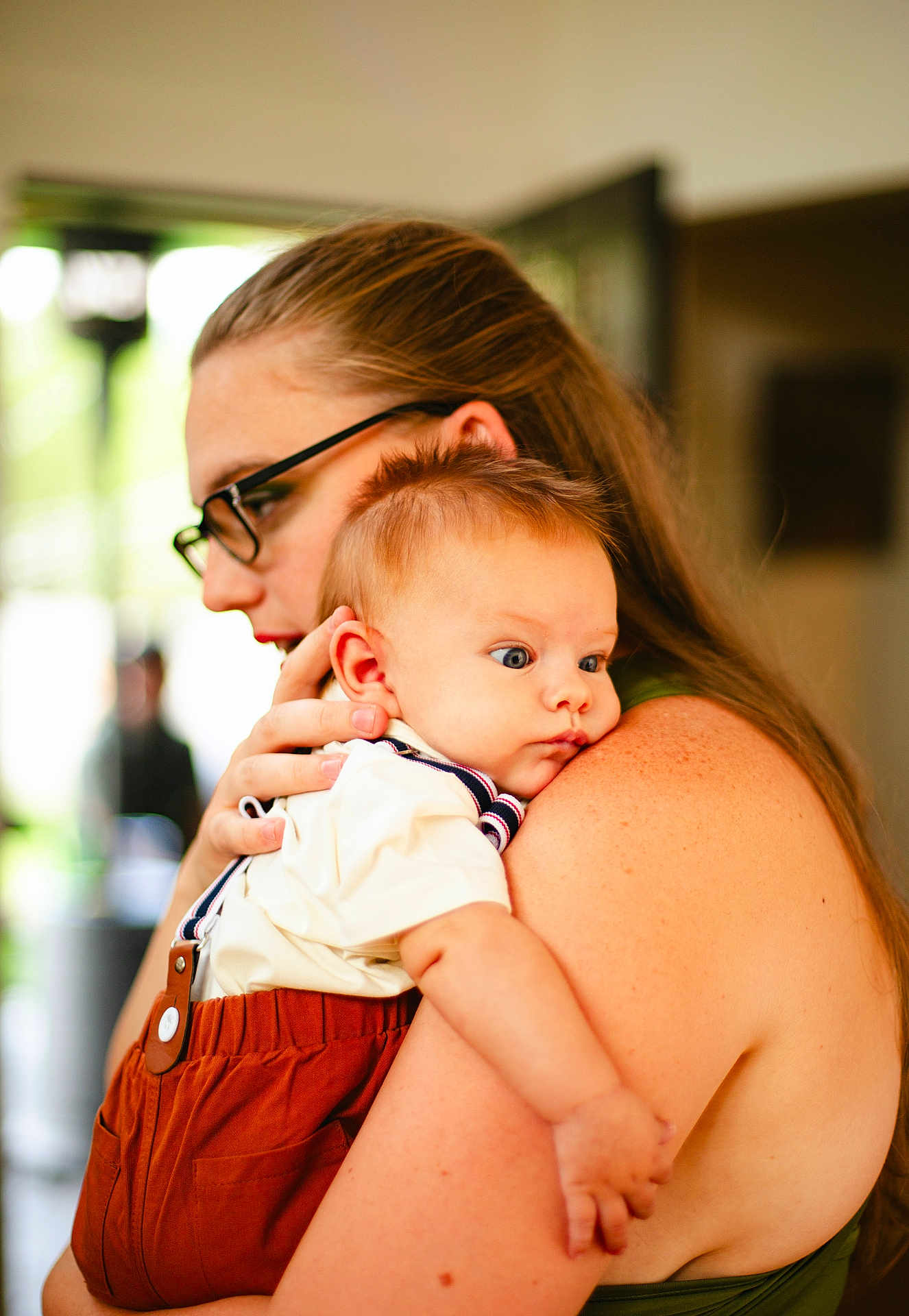 Keith is registered to the contest to win money with this photo: baby, woman, glasses, indoor, holding, shoulder, suspenders, white_shirt, brown_clothing, face, skin, hair, person, child, portrait, closeup, love, family, affection, warm_light