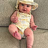 baby, infant, hat, romper, couch, fabric, skin, face, eyes, legs, feet, hand, sitting, child, cute, expression, indoors, texture, scrape, clothing
