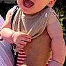 arm, baby, background, child, clothing, daylight, face, greenery, hand, happy, holding, human, laughing, nature, outdoor, person, skin, sleeveless, smile, sunlight