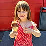 child, cone, cute, face, food, girl, hair, happy, holding, ice_cream, necklace, outdoor, pavement, portrait, red_dress, smile, summer, sunlight, sweet, wall