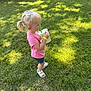 Hollis is registered to the contest to win money with this photo: toddler, child, blonde_hair, pigtails, pink_shirt, blue_shorts, white_sandals, grass, outdoor, sunlight, drink, plastic_cup, green_straw, festival, event, people, tent, shade, wristband, summer