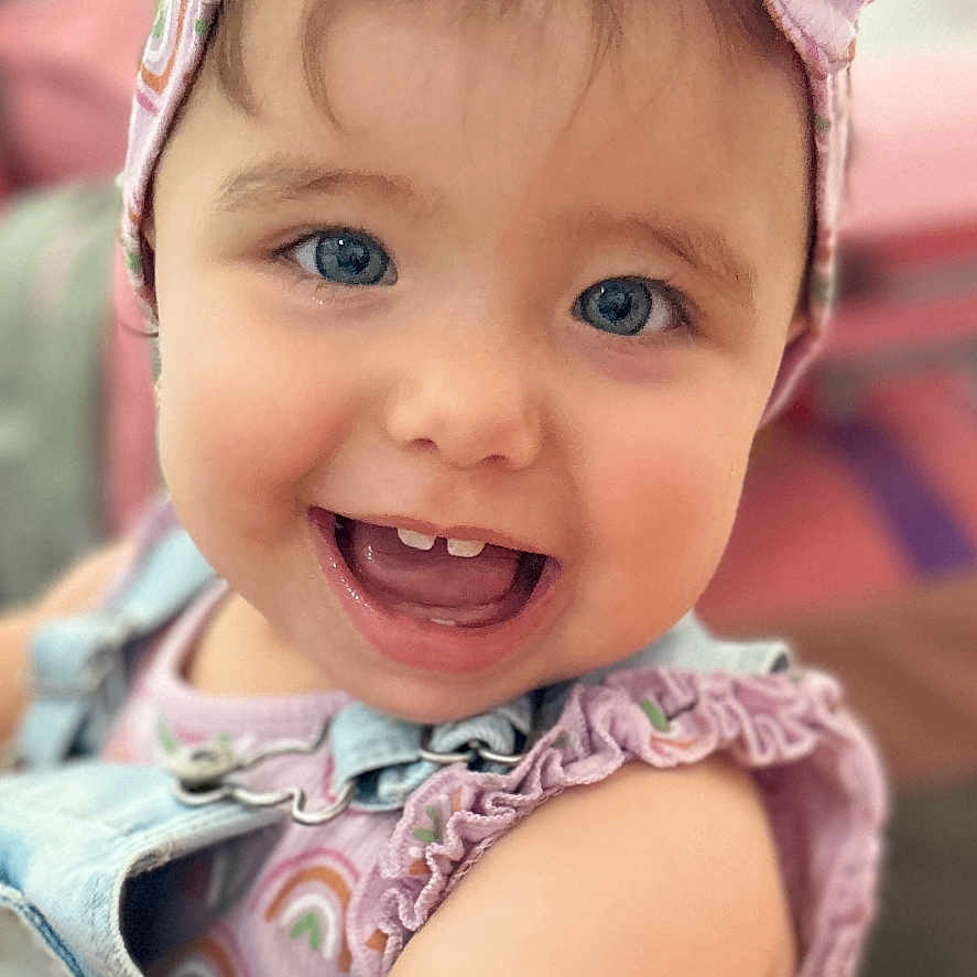 Gabriella is registered to the contest to win money with this photo: accessories, baby, babylaughing, bodypart, bonnet, cap, clothing, dress, face, happy, hat, head, headband, laughing, mouth, person, photography, portrait, smile, sunhat