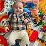 baby, child, plaid_shirt, knit_pants, socks, play_mat, colorful, animal_pattern, toy, smiling, indoor, floor, cute, infant, portrait, happy, lying_down, soft_toys, bright_colors, casual_clothing