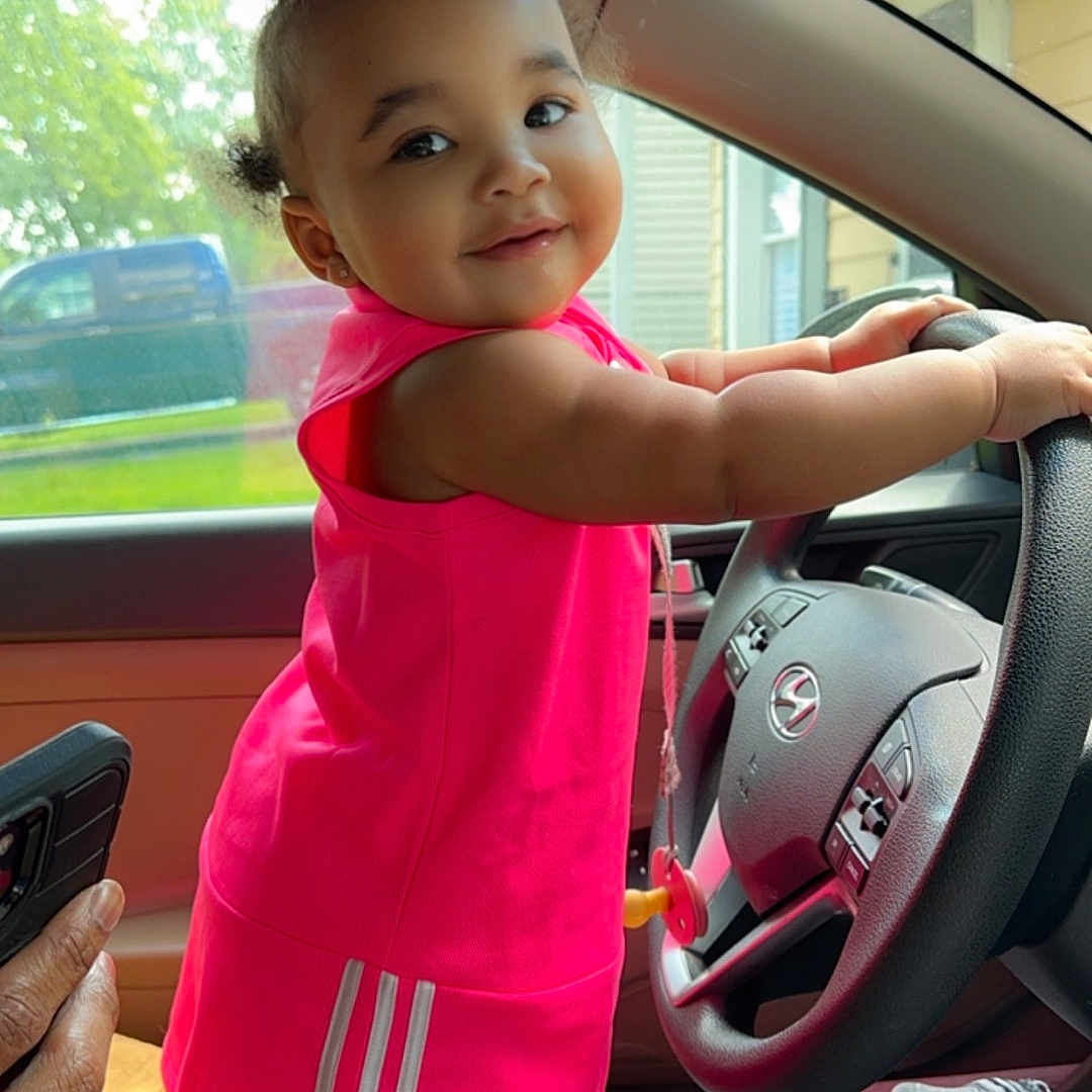 Eliana is registered to the contest to win money with this photo: alloywheel, baby, car, carwheel, clothing, cushion, dress, face, footwear, head, machine, person, photography, portrait, shoe, spoke, tire, transportation, vehicle, wheel