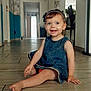 Romy a rejoint le concours — aidez-le/la à gagner de superbes lots ! toddler, denim_dress, smiling, sitting, floor, hallway, headband, child, indoor, happy, barefoot, wooden_floor, furniture, person, portrait, home, cute, baby, girl, casual